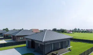 Nowoczesne domy z szarymi dachami. Widać obróbkę dachu wiatrownica, która chroni przed silnym wiatrem.