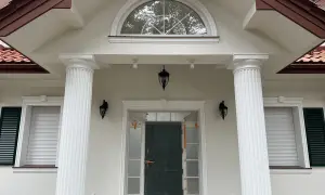 Elegancki pilaster zdobi fasadę domu, wspierając dach nad wejściem.