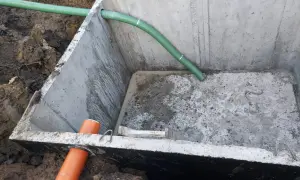 Szambo betonowe 10m3 cena z montażem. Instalacja wkopana w ziemię, widoczne rury doprowadzające.