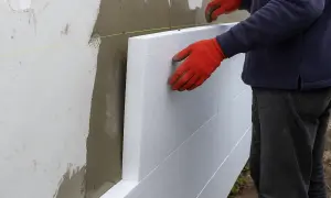 Układanie styropianu na ścianie. Siatka i klej czekają, by obniżyć cenę robocizny.