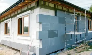 Budowa domu: ocieplenie elewacji szarym styropianem, rusztowanie, okna.