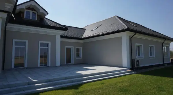 Nowoczesny dom z tarasem i trawnikiem. Elegancki gzyms podkreśla architekturę budynku.