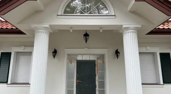 Elegancki pilaster zdobi fasadę domu, wspierając dach nad wejściem.