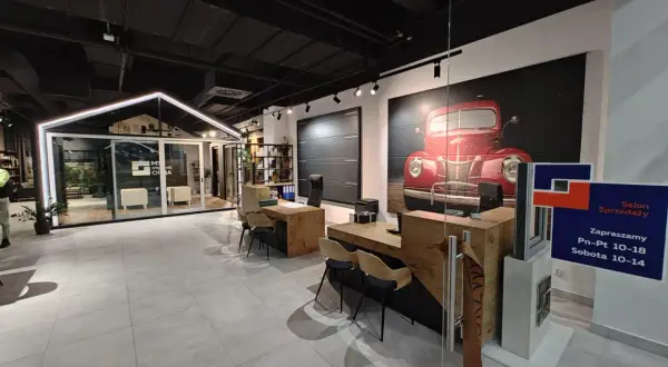 Nowoczesny salon okien i drzwi z ekspozycją, grafiką czerwonego auta i ladą sprzedażową.
