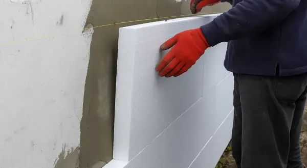 Układanie styropianu na ścianie. Siatka i klej czekają, by obniżyć cenę robocizny.