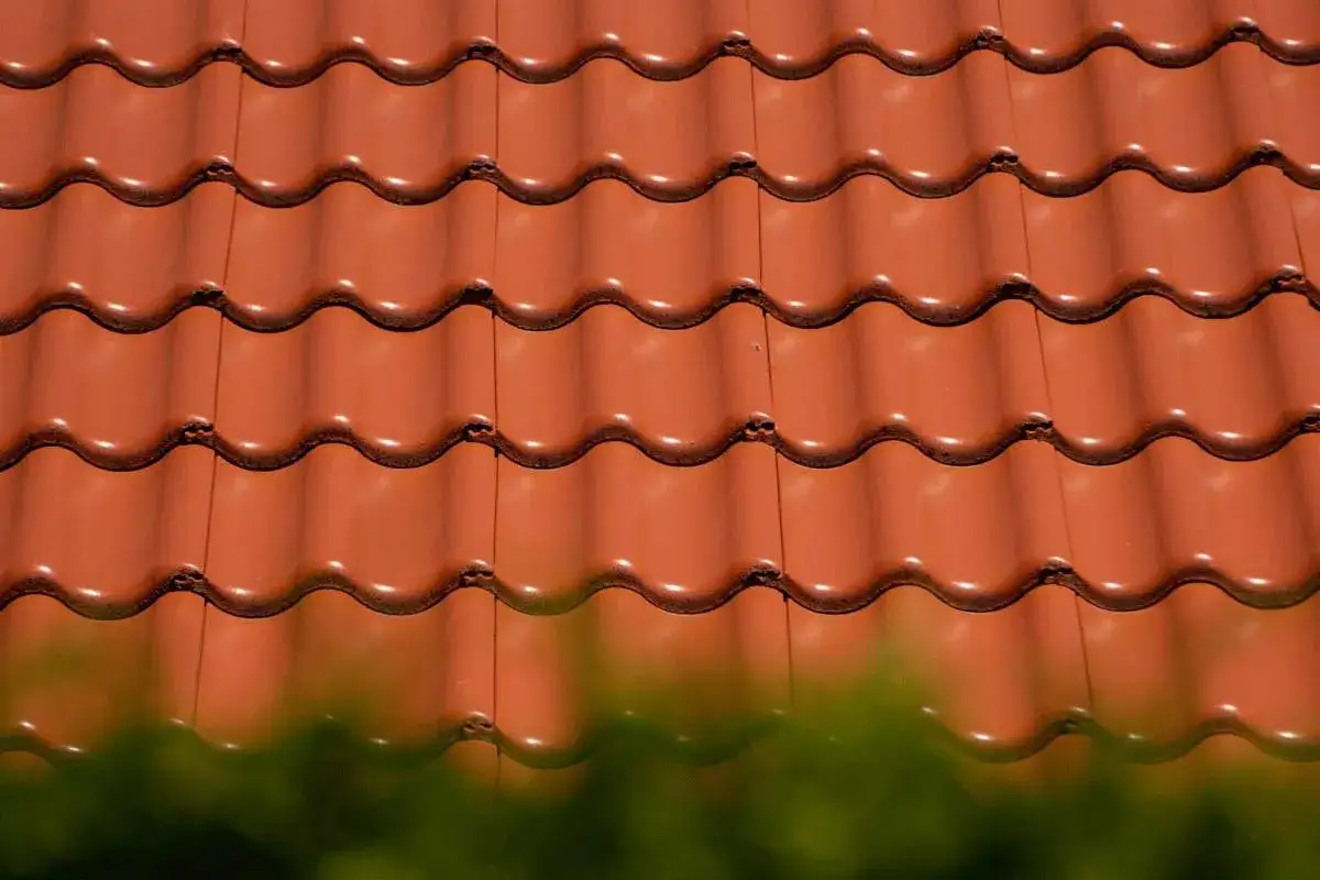Czerwone, faliste dachówki ceramiczne tworzą wzorzystą powierzchnię dachu. Różne rodzaje dachówek zapewniają estetykę i ochronę.