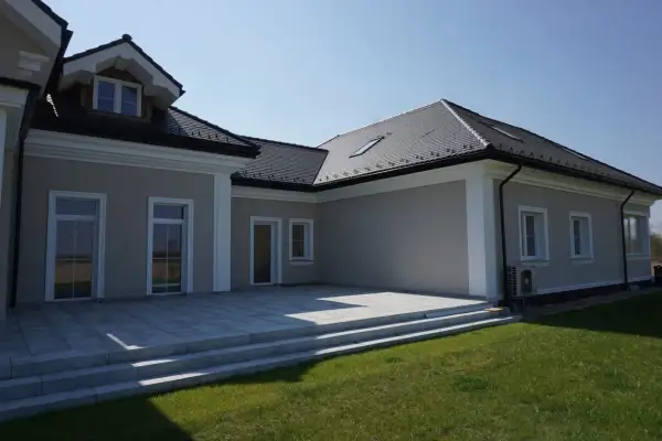 Nowoczesny dom z tarasem i trawnikiem. Elegancki gzyms podkreśla architekturę budynku.
